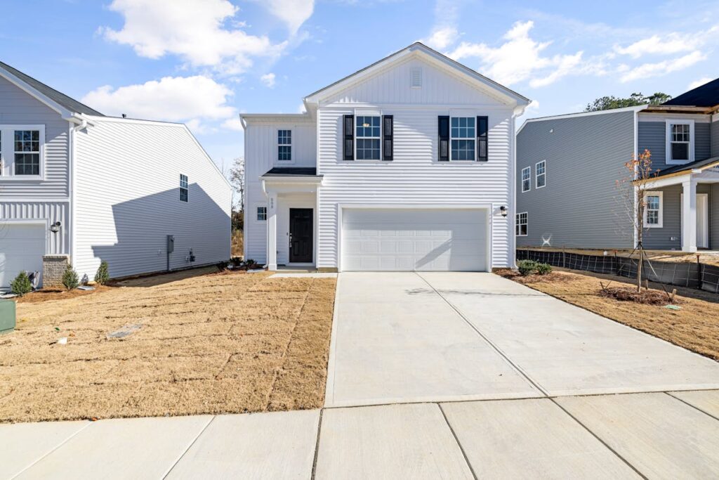 Contemporary white house with garage, blue sky, and landscaped yard.